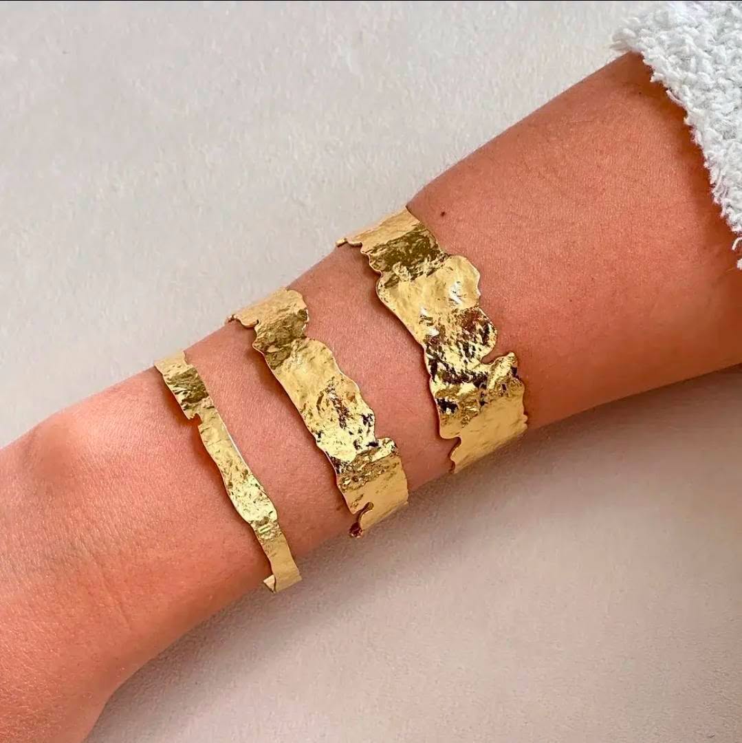 Hammered gold cuffs stacked on a wrist